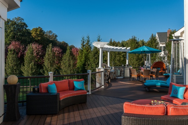 backyard deck ideas - a backyard deck with wicker couches and a blue umbrella